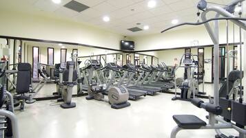 Un gimnasio con cintas de correr, máquinas de pesas y pesas sueltas.