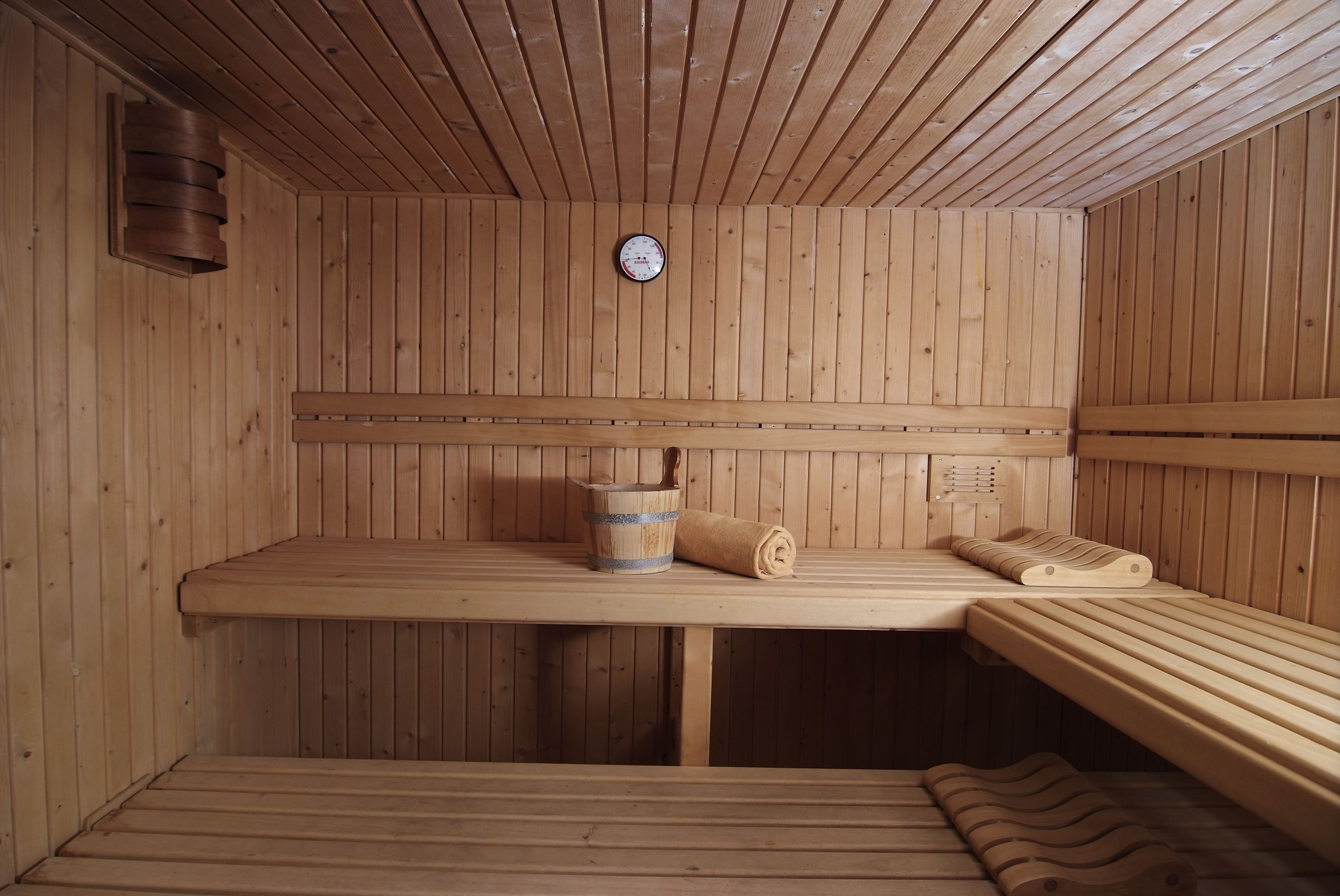 A wooden sauna with benches and a wooden bucket.