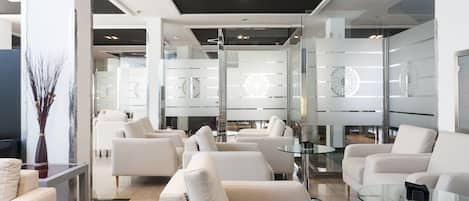 A modern living room with a sofa, armchairs, and a glass coffee table.