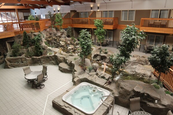An indoor setting with a hot tub, seating area, and a rock garden with plants. - C'mon Inn Hotel & Suites (Grand Forks)