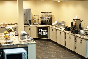 A hotel kitchen with a coffee station, a waffle maker, and a refrigerator. - C'mon Inn Hotel & Suites (Grand Forks)