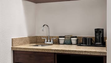 A kitchen with a granite countertop, stainless steel sink, and a coffee maker.