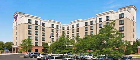A multi-story hotel with a parking lot in front.