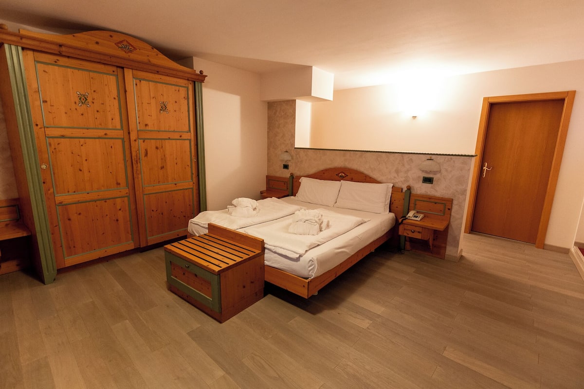 Een slaapkamer met een houten bed, een kledingkast van hout en een nachtkastje.