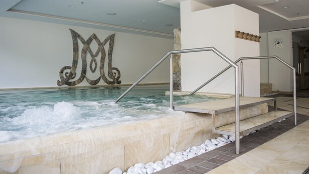 Een jacuzzi met een stenen muur en een metalen trap die leidt naar een gebied met kiezelstenen.