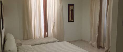 A bedroom with two beds, a ceiling fan, and a framed picture on the wall.