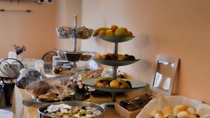 Mesa de buffet com diversos alimentos e uma televisão fixada na parede.