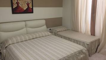 Standard trippelrum | DuntÀcken, minibar, vÀrdeförvaringsskÄp pÄ rummet och skrivbord