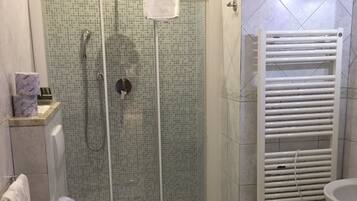 A bathroom with a shower, toilet, sink, and a towel rack.