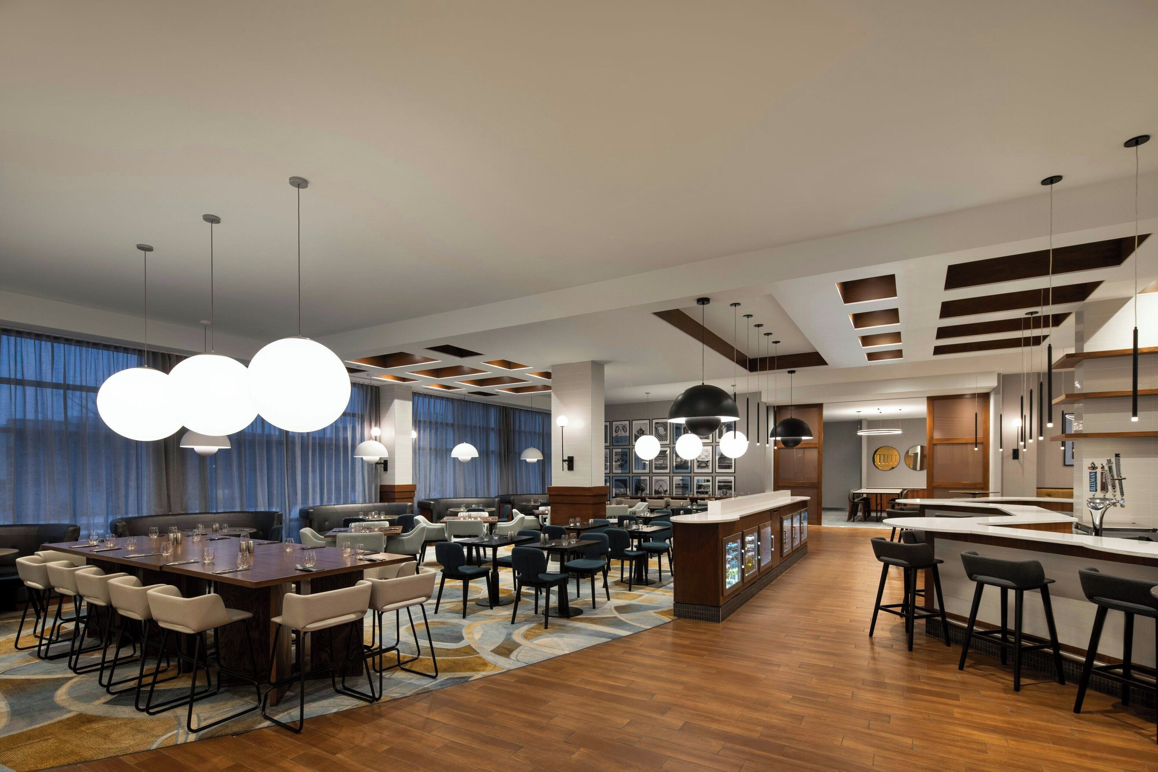 Een moderne hotel lobby met een centraal gelegen eetgedeelte, bar en zitplaatsen.