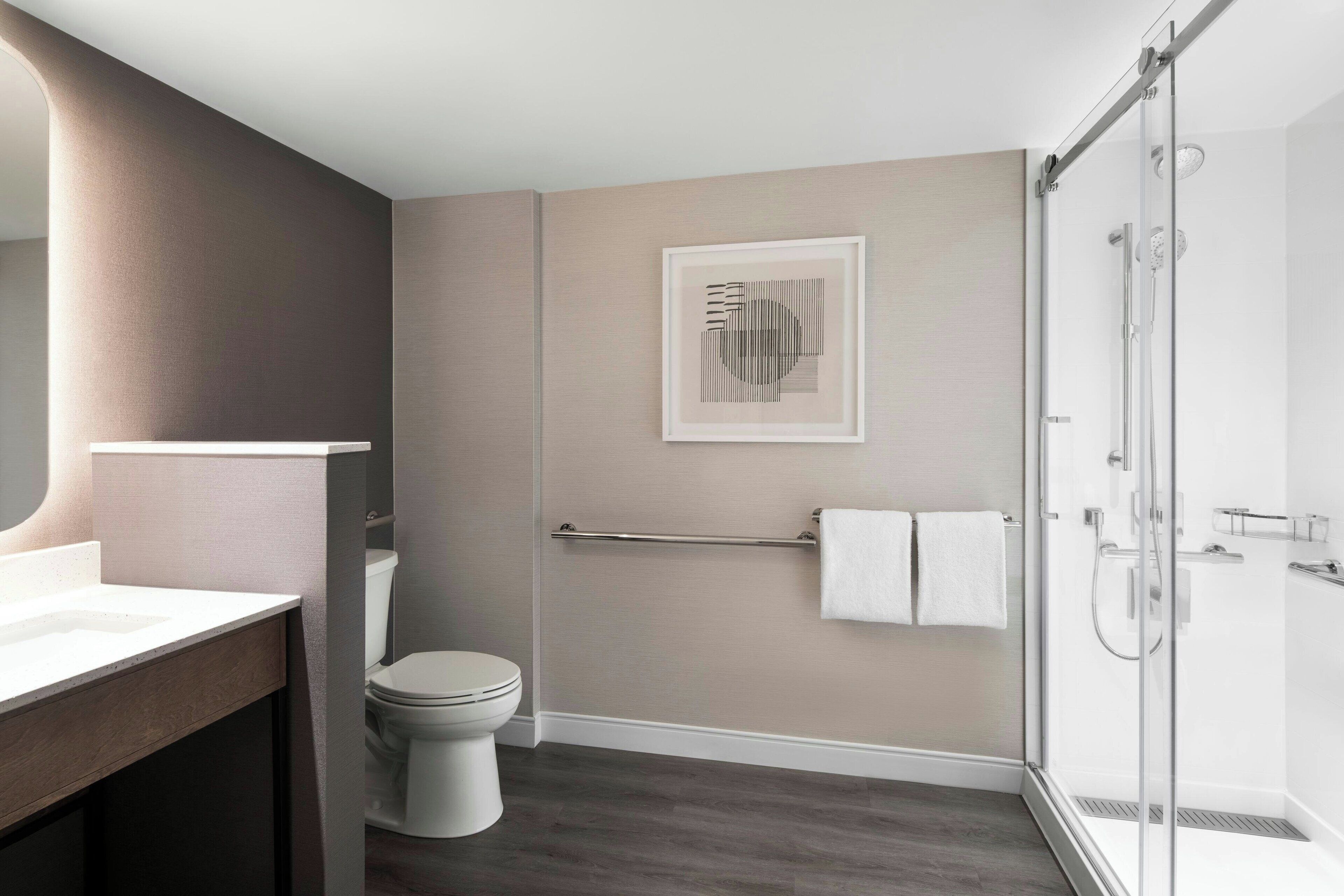 A modern bathroom with a toilet, a shower, and a sink.