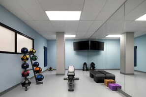 Een sportschool met trainingsapparatuur, een televisie en een spiegel.
