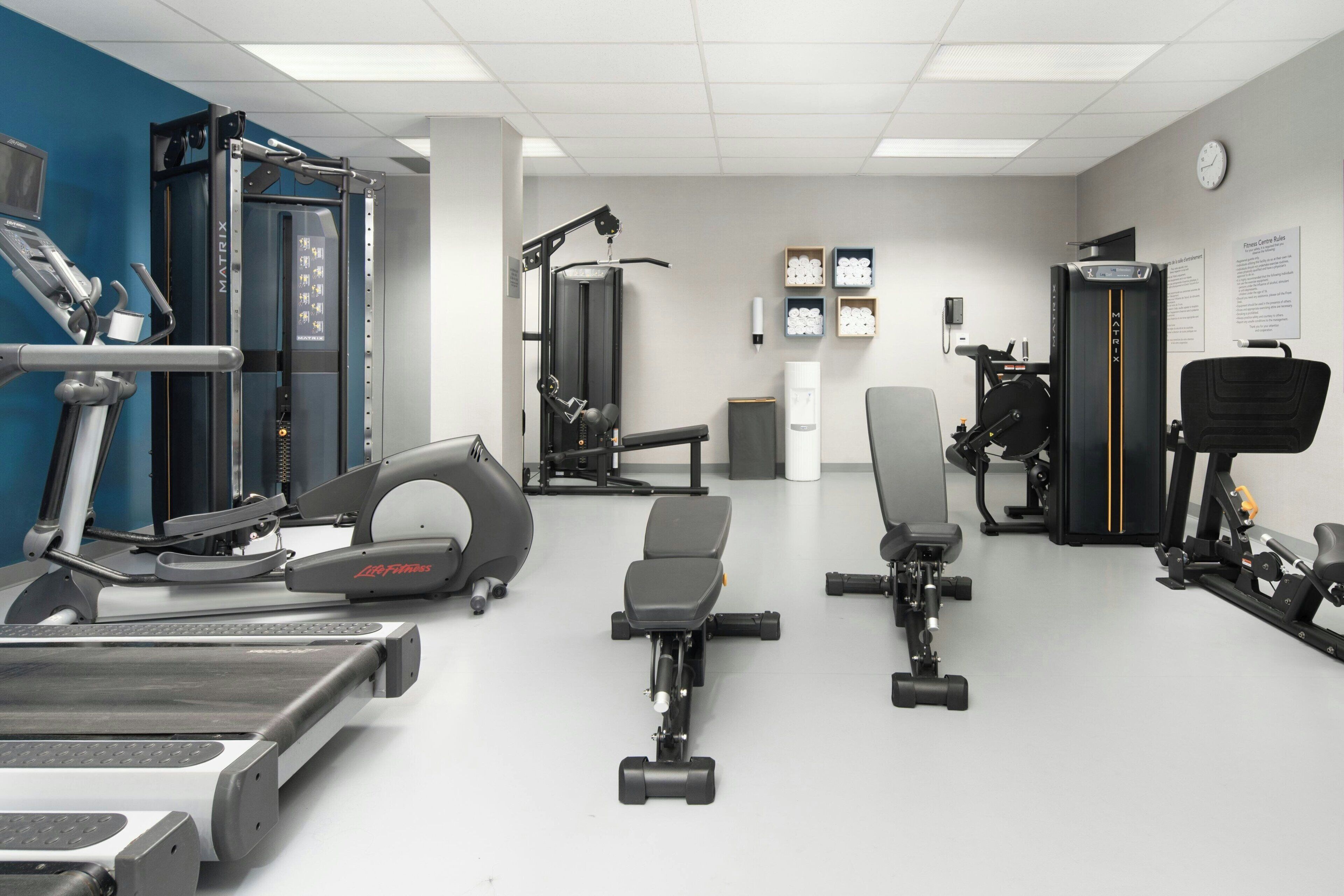 A gym with various exercise equipment including treadmills, weight machines, and free weights.