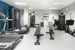 A gym with various exercise equipment including treadmills, weight machines, and free weights.