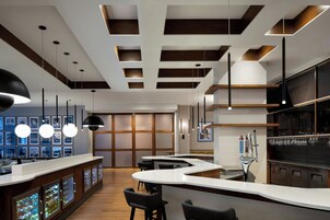 A modern bar area with a curved counter, pendant lighting, and a bar stool seating arrangement.