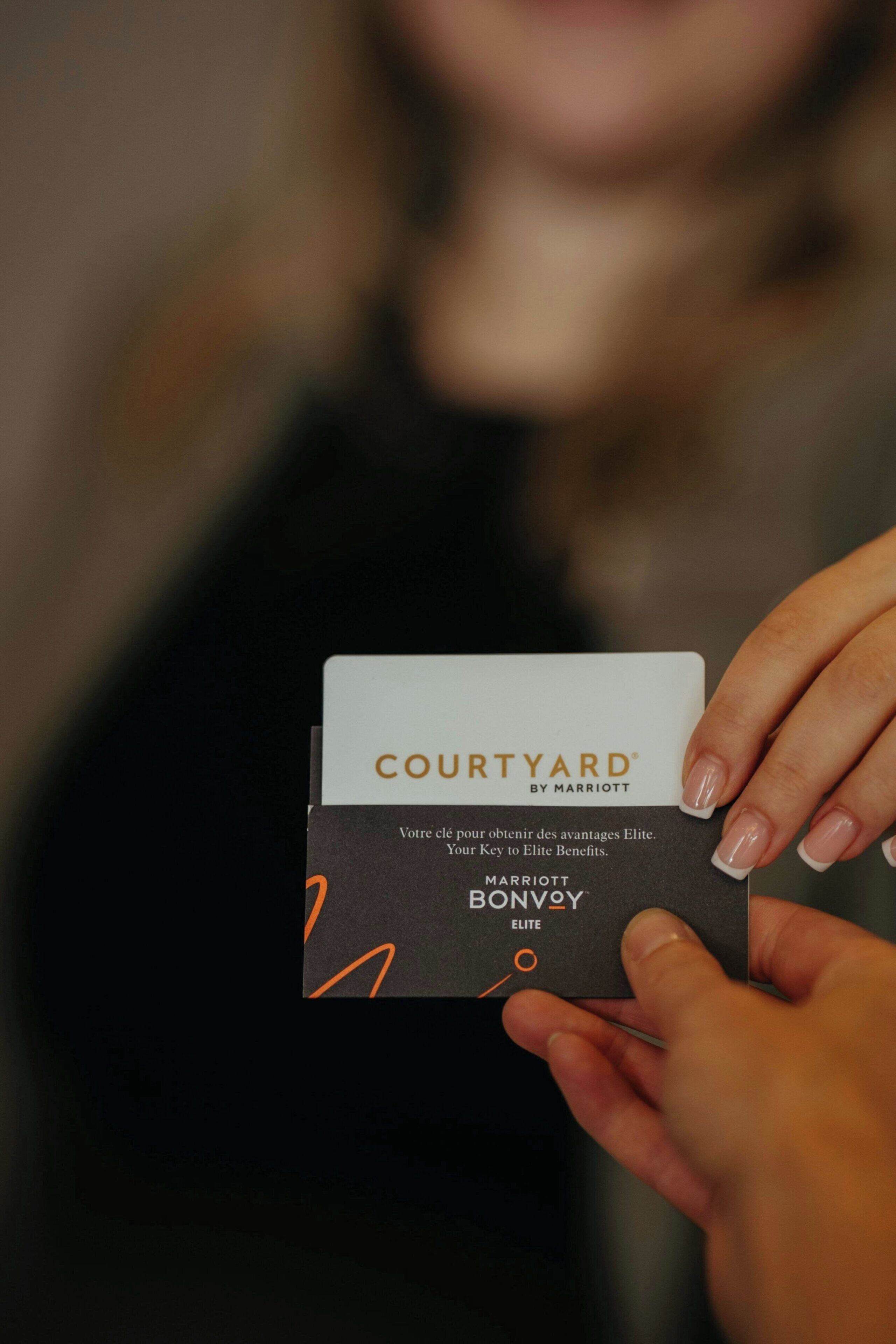 Una persona sostiene una tarjeta con el texto 'COURTYARD BY MARRIOTT' y 'MARRIOTT BONVOY ELITE'.