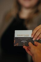 Une personne tenant une carte sur laquelle figurent les inscriptions « COURTYARD BY MARRIOTT » et « MARRIOTT BONVOY ELITE ».