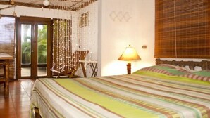 Una habitación con una cama, una silla, una lámpara y una puerta que da al exterior.