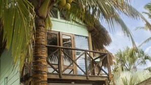Un edificio de dos pisos con balcón, rodeado de palmeras.