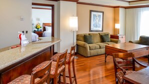 Habitación de hotel con comedor, sofá, mesa de centro y televisión.