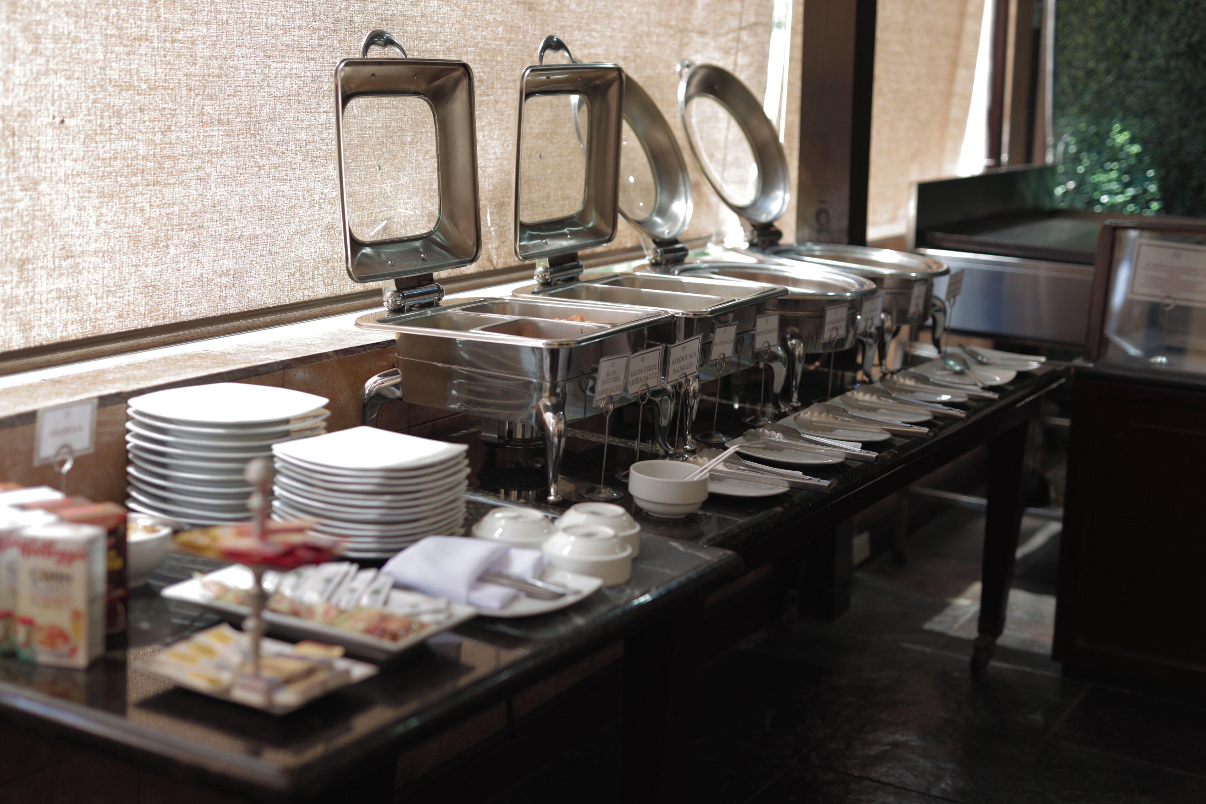 A buffet setup with multiple serving stations, plates, bowls, and utensils.