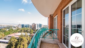 Un balcón con vista a la ciudad, barandilla verde y el logotipo del Hotel Casa Veranda.