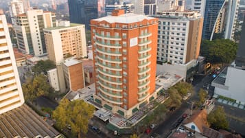 A high-rise building with multiple balconies, surrounded by other buildings and trees.