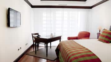 A hotel room with a bed, a desk, a chair, a television, and a window with curtains.