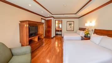 A hotel room with two beds, a TV, wooden furniture, and a hallway leading to a bathroom.