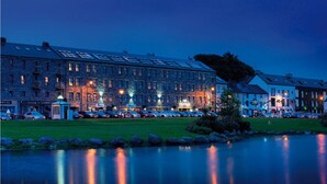 A large hotel with multiple floors, a parking lot, and a reflection in a body of water. - Westport Coast Hotel (Westport)