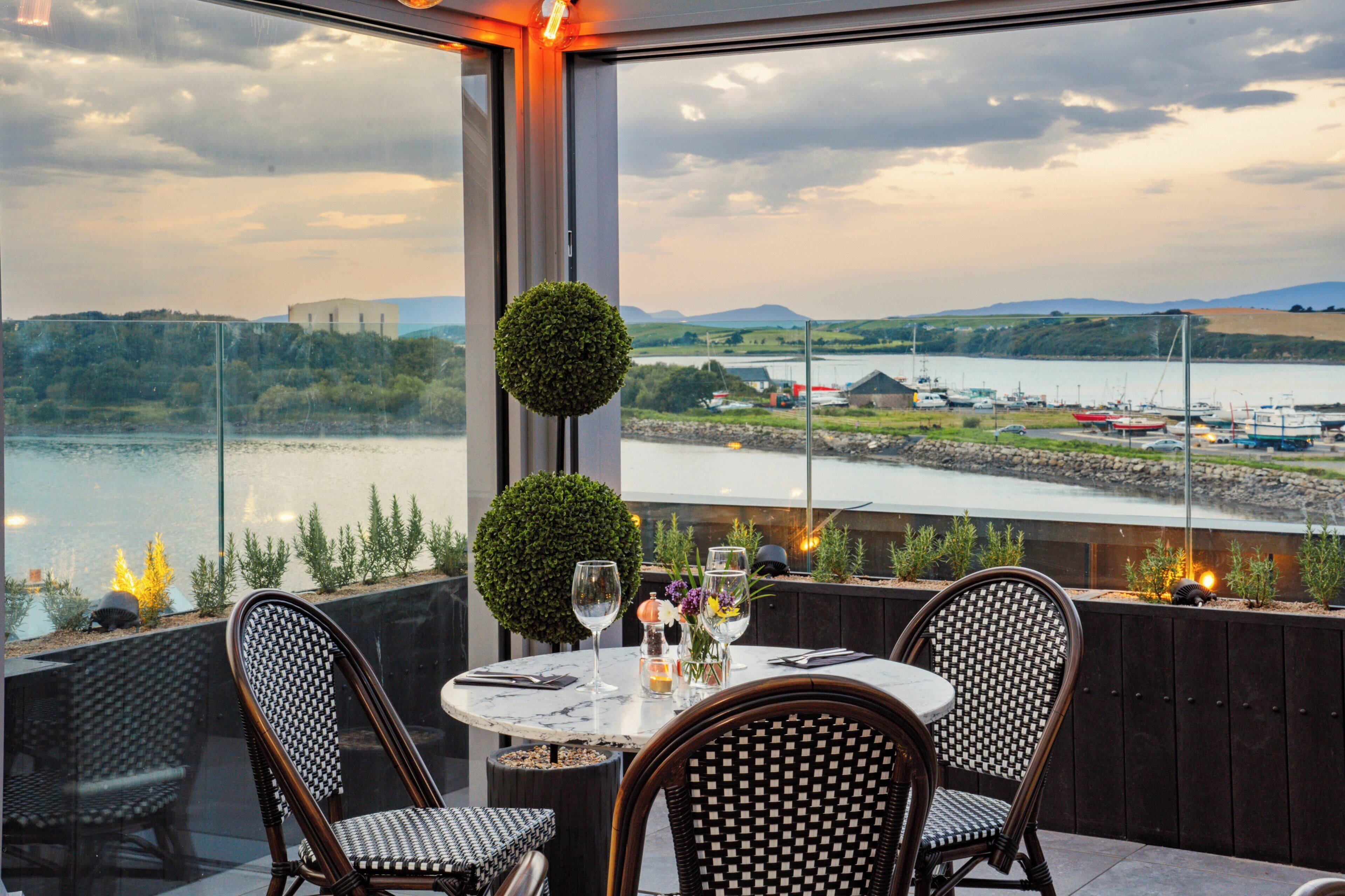 Una mesa para dos con vista a un río y edificios al fondo.