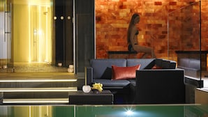 A modern lobby with a glass coffee table, a blue sofa with red cushions, and a wall with a mosaic pattern. - Westport Coast Hotel (Westport)
