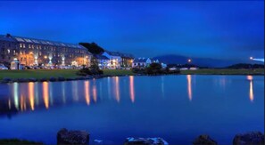 A large hotel with a reflective lake in front, featuring a well-lit building and a calm water surface. - Westport Coast Hotel (Westport)