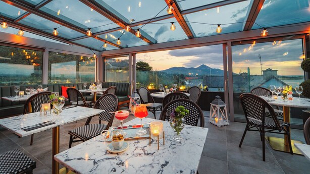 A restaurant with outdoor seating, large windows, and string lights. - Westport Coast Hotel (Westport)
