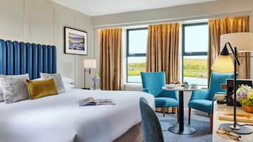 A hotel room with a large bed, a desk with a lamp, and a view of the outdoors.