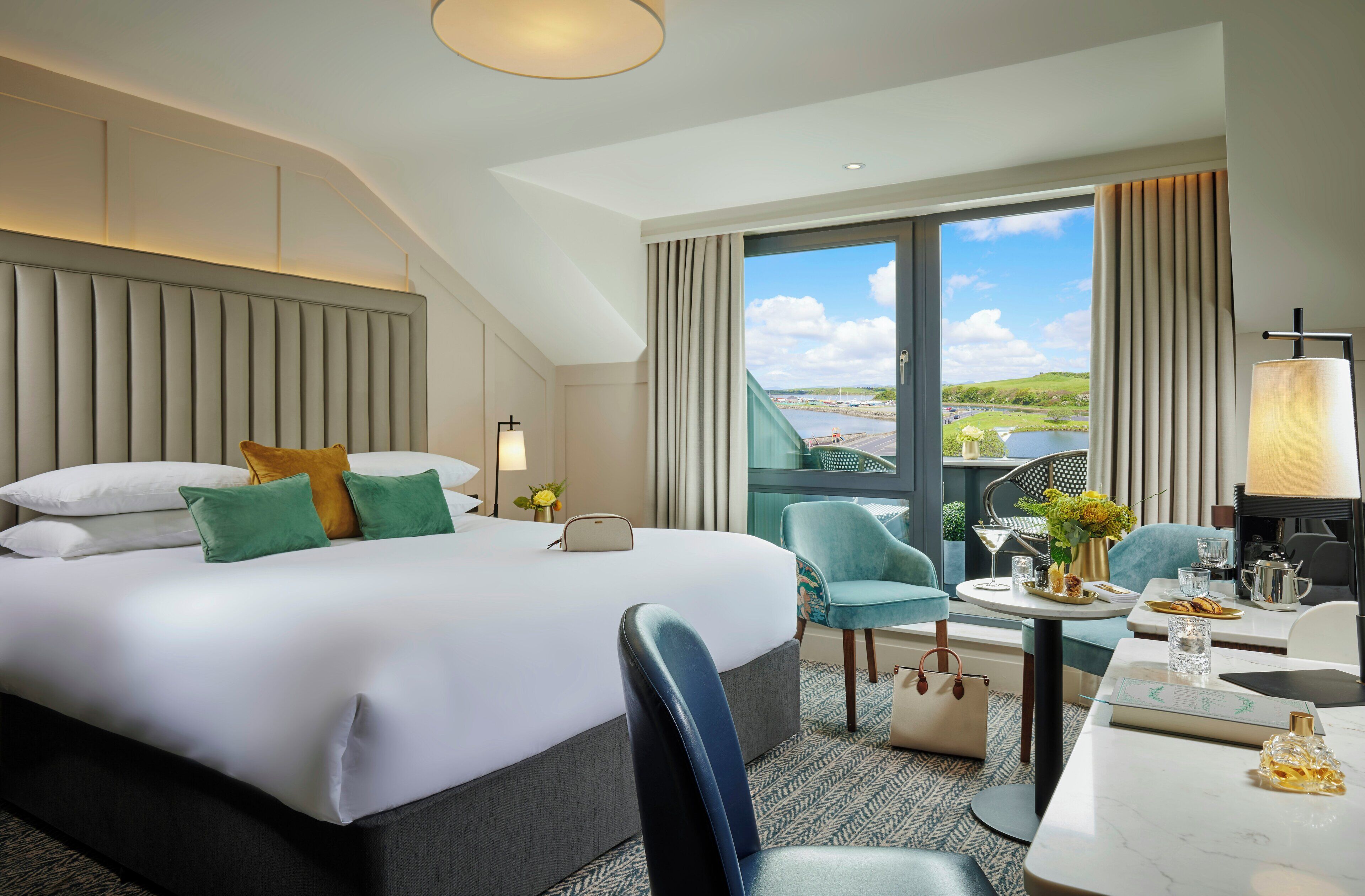 A hotel room with a large bed, a sitting area with a table, and a view of a body of water.