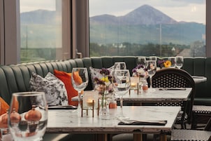 Comedor con una mesa dispuesta para dos personas, con vistas a las montañas a través de amplios ventanales.