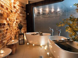 Un baño moderno con dos tinas separadas, una pared de ladrillo y un espejo grande.