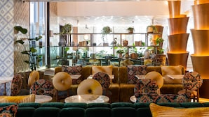 Un área de descanso moderna con sofás verdes, cojines estampados y diversos objetos decorativos en estanterías.