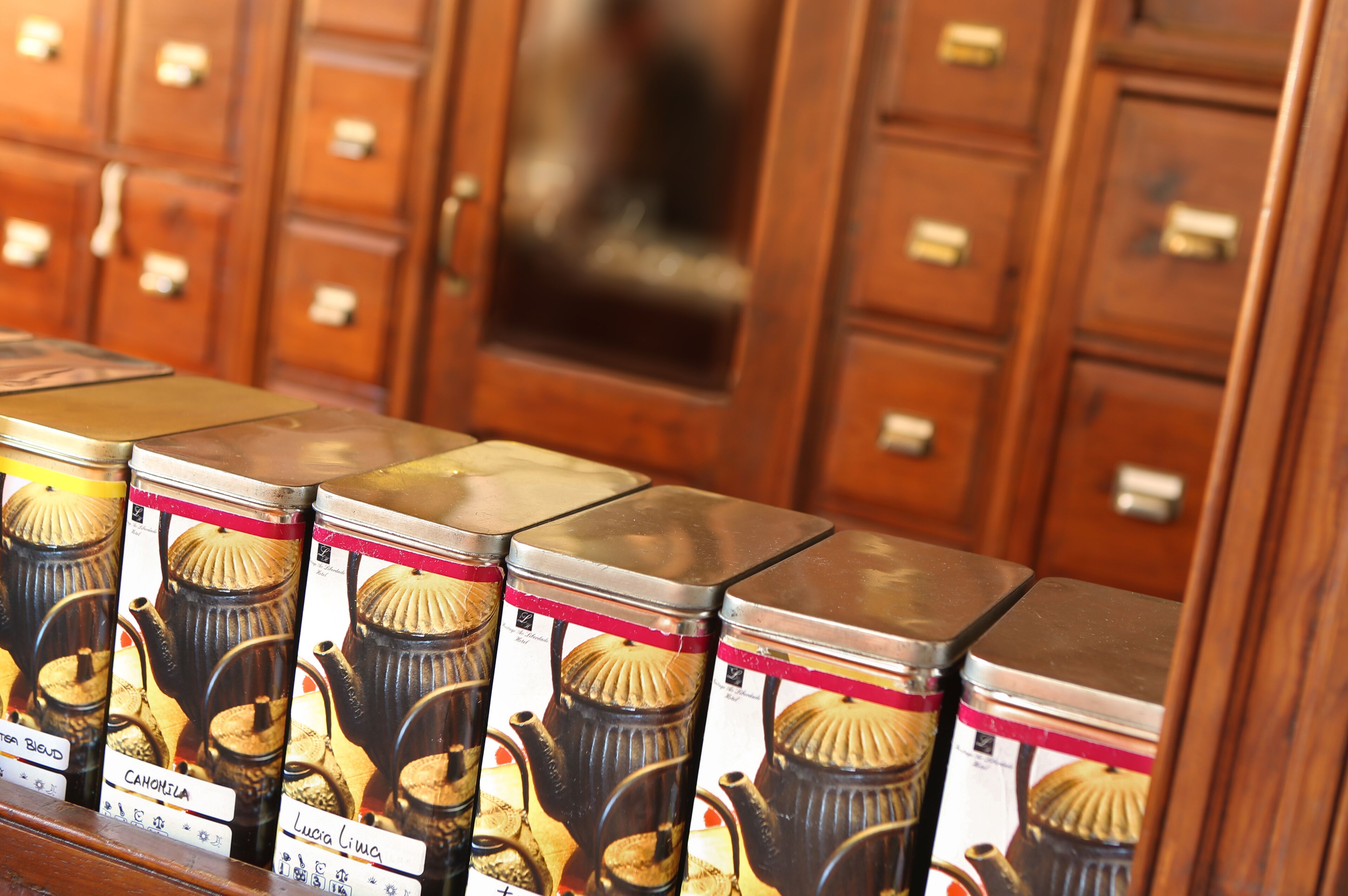 A row of tea tins with labels on a wooden shelf.