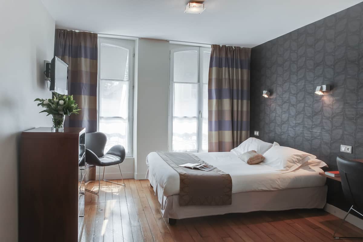 Une chambre d’hôtel moderne, dotée d’un grand lit, d’un bureau et d’une chaise.