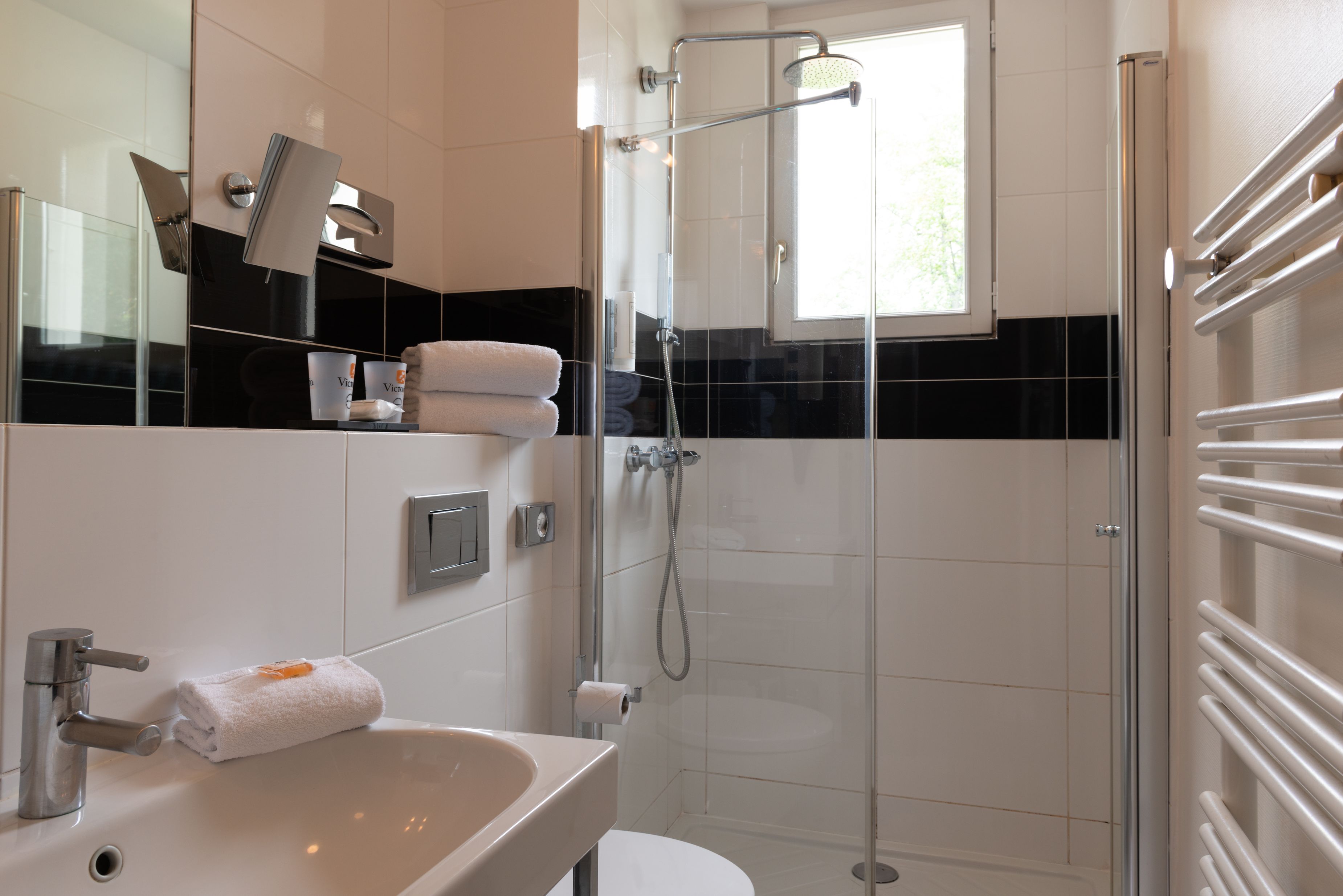 Un baño moderno con ducha envuelta en vidrio, un lavamanos blanco y un espejo grande.