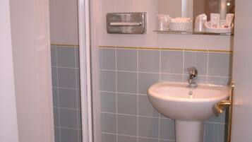 Un baño con un lavabo blanco, un espejo y un estante con artículos de aseo.