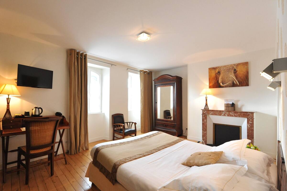 Une chambre d’hôtel équipée d’un lit, d’un bureau, de chaises, d’une télévision et d’une cheminée.