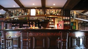 A bar area with a curved counter, multiple shelves of bottles, and bar stools.