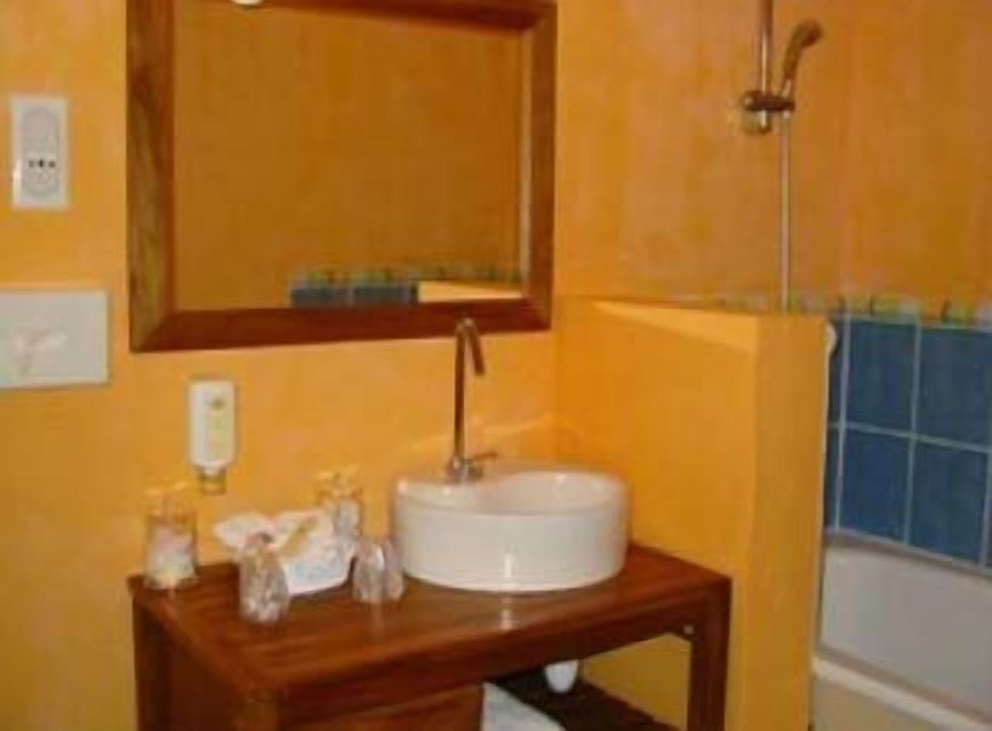 Ein Badezimmer mit einem weißen Waschbecken, einem Holz-Waschtisch und einem Spiegel.
