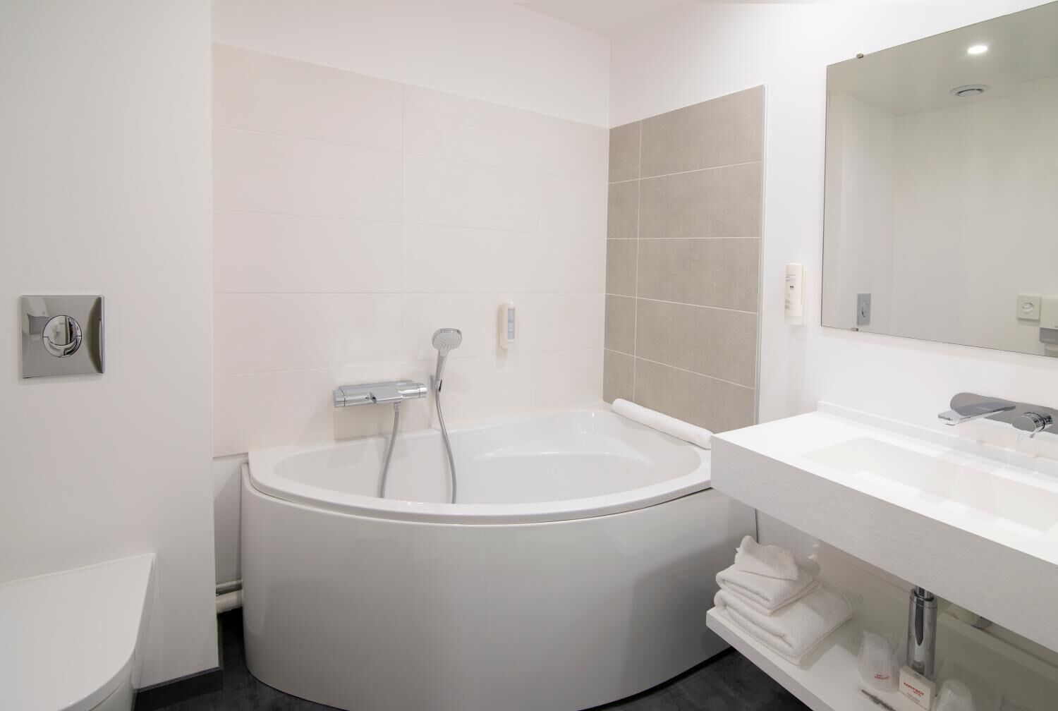 A modern bathroom with a freestanding bathtub, a white sink, and a large mirror.