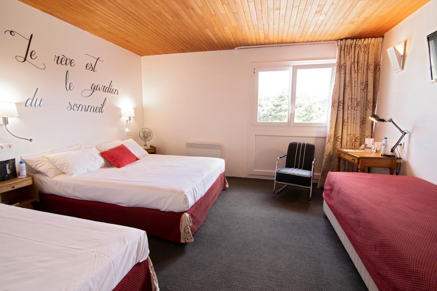 A hotel room with two beds, a chair, a desk, and a window with curtains.