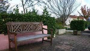A wooden bench with a lattice backrest, placed on a cobblestone path.