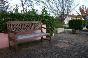 Um banco de madeira com encosto treliçado, colocado sobre um caminho de pedras.